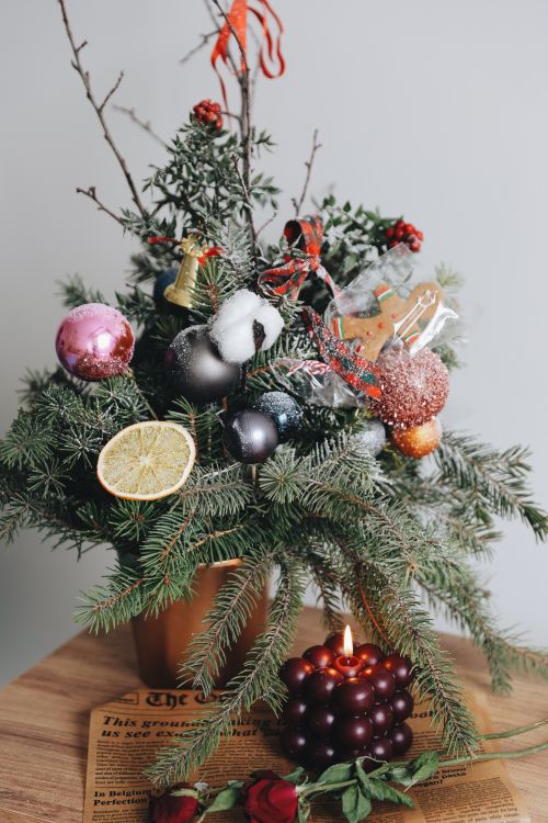 Free Rustic holiday arrangement with evergreen branches, ornaments, and a lit candle, ideal for festive decor. Stock Photo