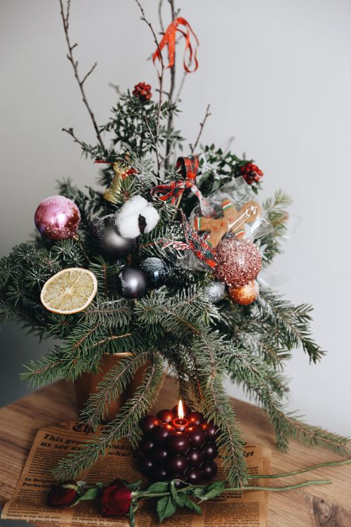 Free Festive Christmas decoration with pine branches, ornaments, and a lit candle on a wooden surface. Stock Photo