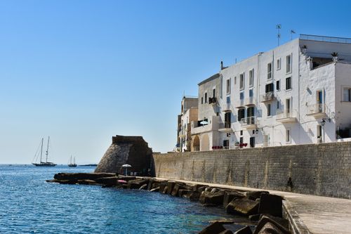 Free Picturesque view of Monopoli's waterfront in Apulia, Italy with clear blue skies and sailboats. Stock Photo