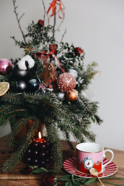 Free Cozy holiday setup with evergreen branches, ornaments, a candle, and a festive mug. Stock Photo