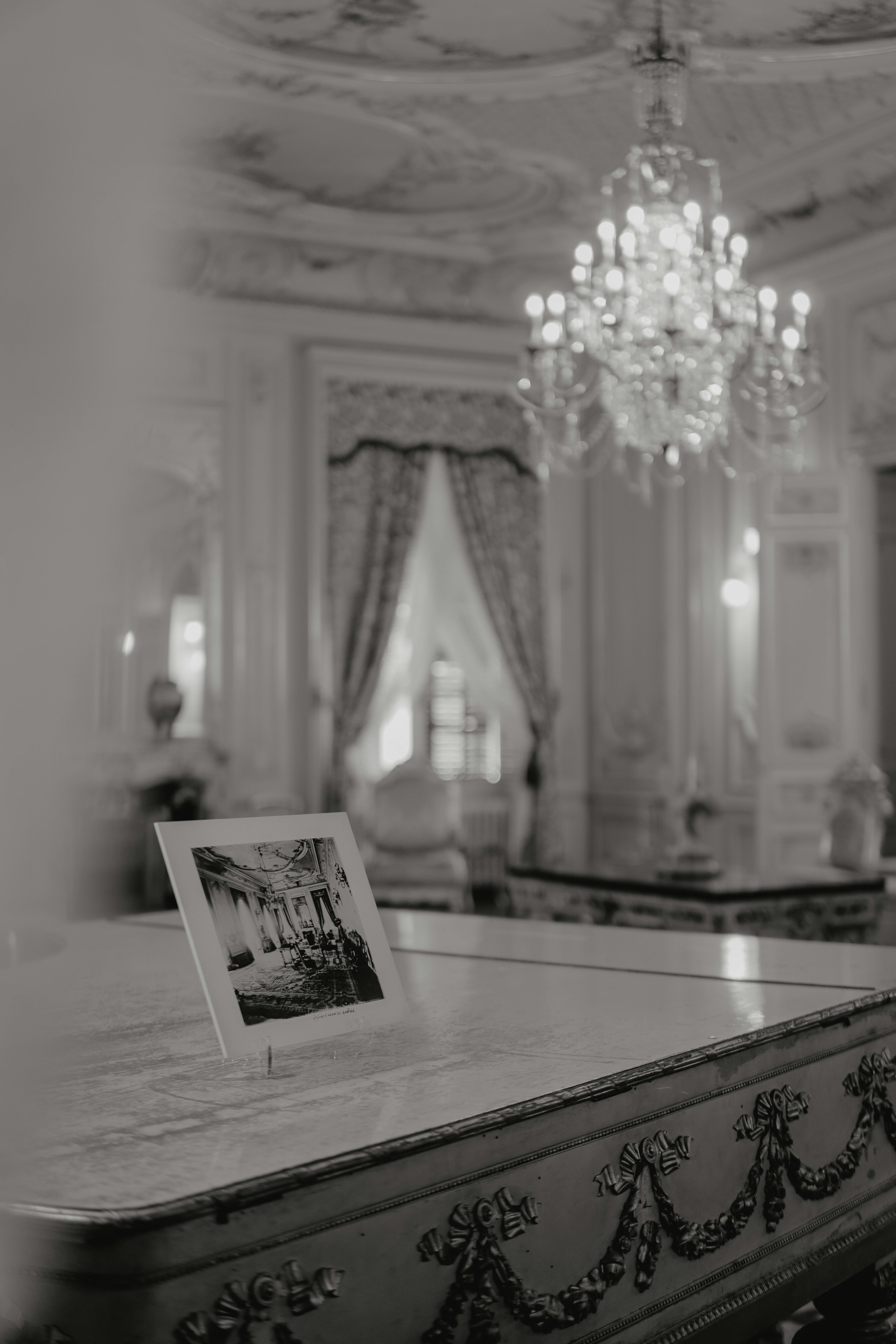 bezplatná Sofistikovaná černobílá fotografie vintage interiéru s lustrem a klasickým dekorem. Základová fotografie