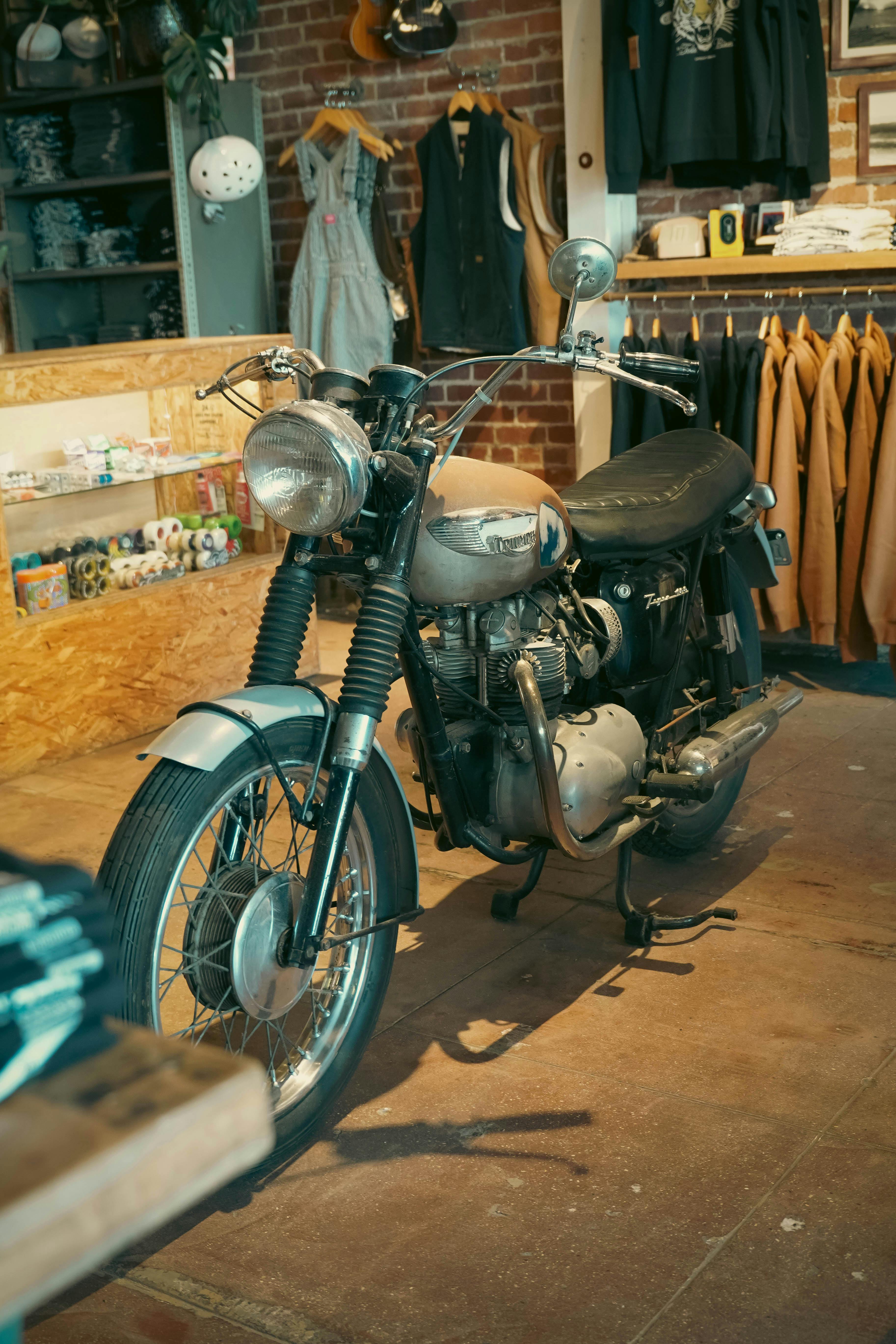 A classic motorcycle displayed in a retro-themed clothing store with vintage decor.