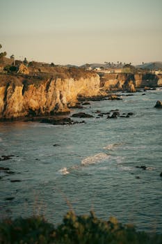 Golden sunlight on the rocky cliffs of Pismo Beach, California, overlooking the Pacific Ocean.
