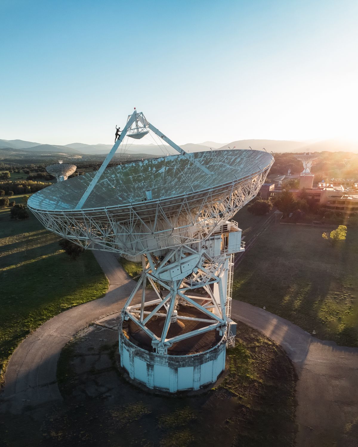 A towering satellite dish in a field at sunrise, highlighting technology and exploration. Illustrative editorial photograph.