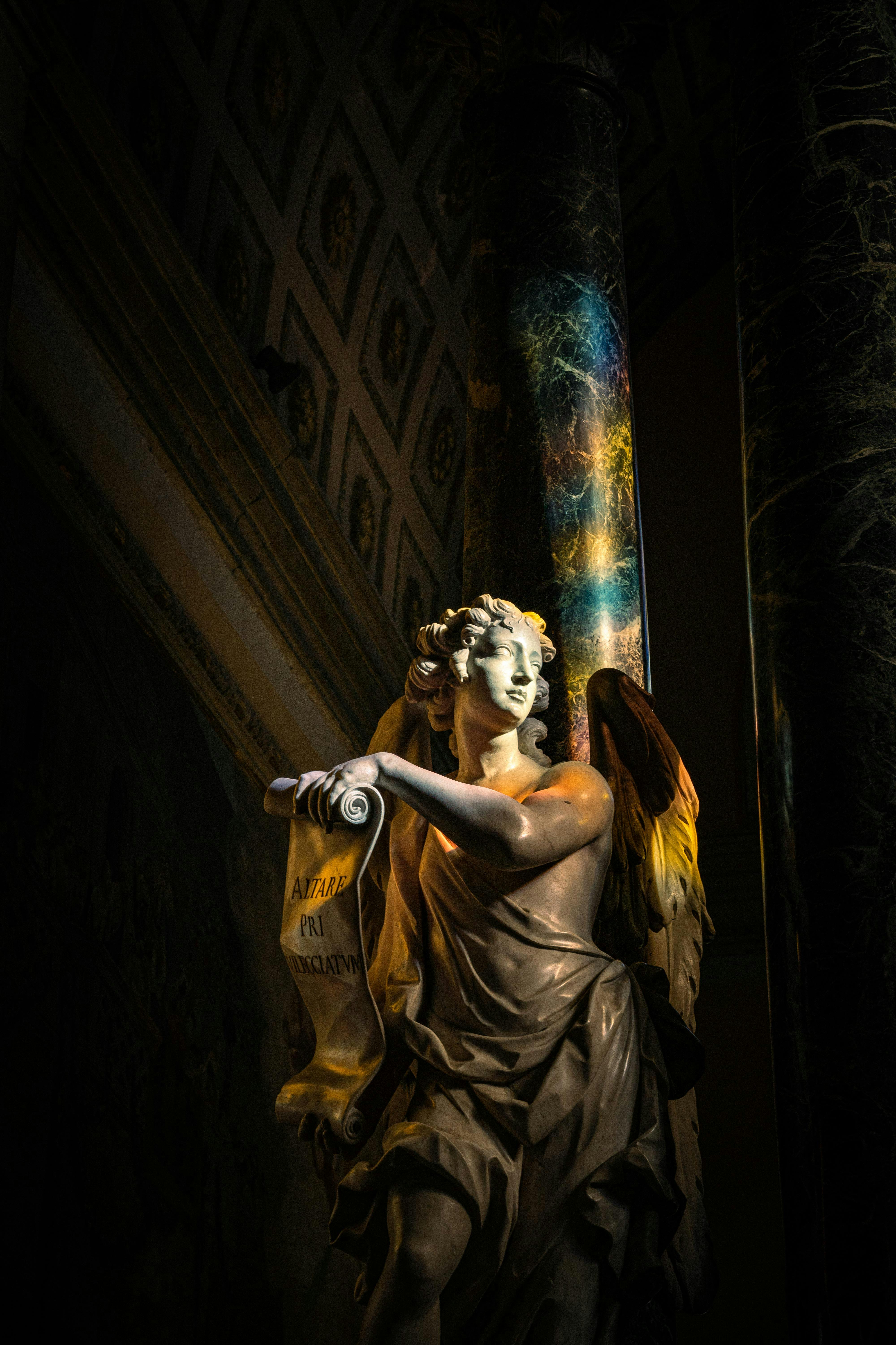 A stunning angel sculpture illuminated in dramatic and colorful lighting with artistic detail.