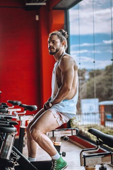 Athletic young man in casual gym wear relaxing on a stationary bike in a modern indoor setting.