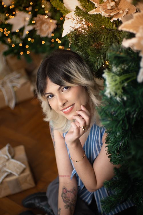 Free Smiling woman with short hair poses by a decorated Christmas tree indoors. Stock Photo