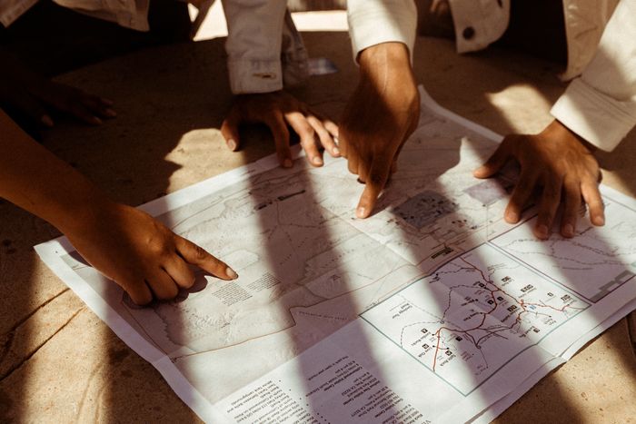 Several hands pointing at a paper map while planning — photo by Wendy Wei on Pexels