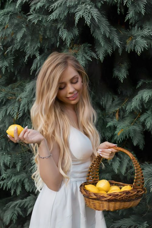 Free A woman holding a basket of lemons in a garden setting, showcasing a fresh and natural vibe. Stock Photo