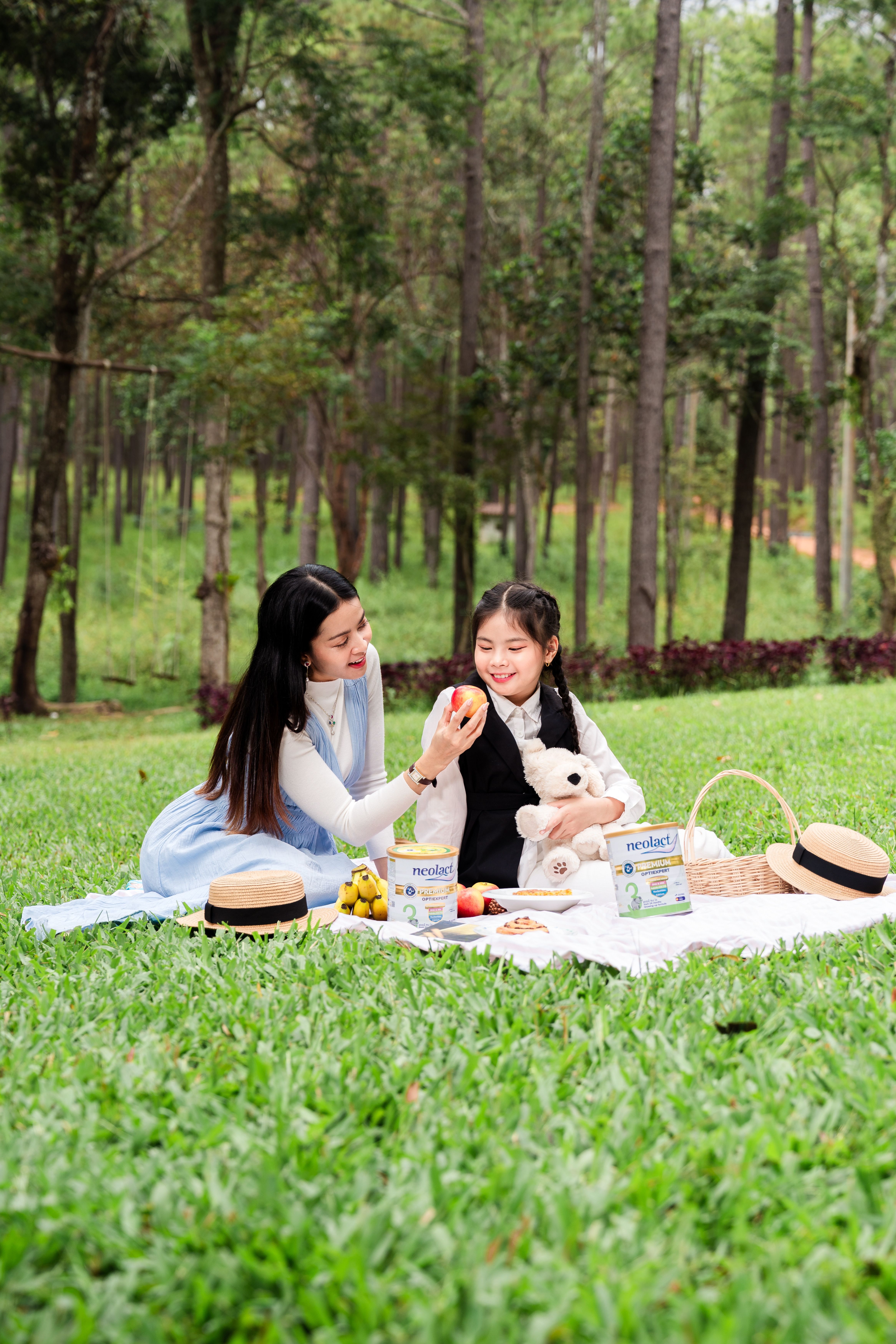 A joyful mother and daughter enjoying a picnic outdoors in Phnom Penh, surrounded by lush greenery.