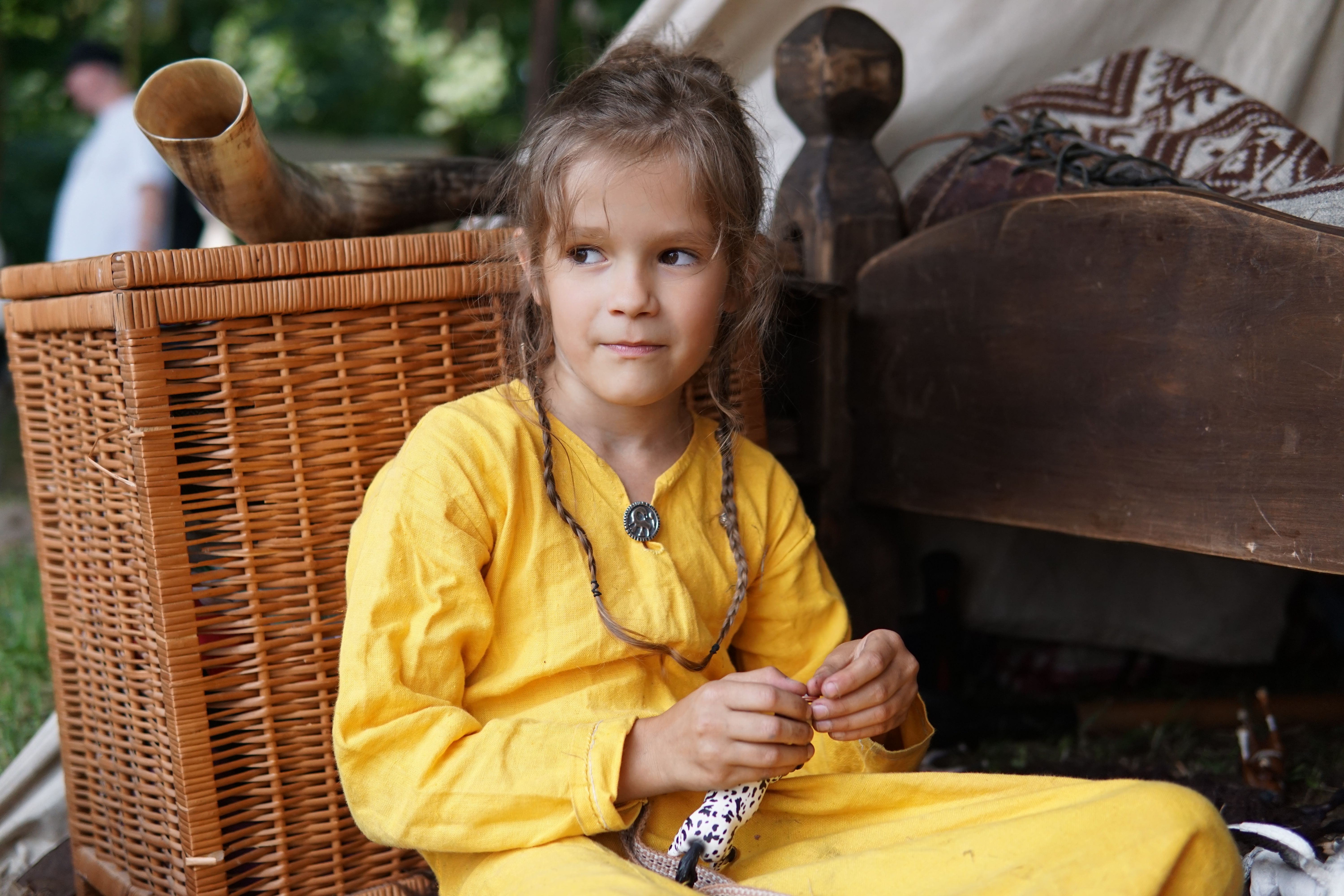 Child in Traditional Costume Sitting Outdoors · Free Stock Photo