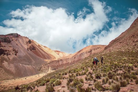 Hikers exploring rugged mountainous terrain under a bright blue sky. Perfect for adventure and travel themes.