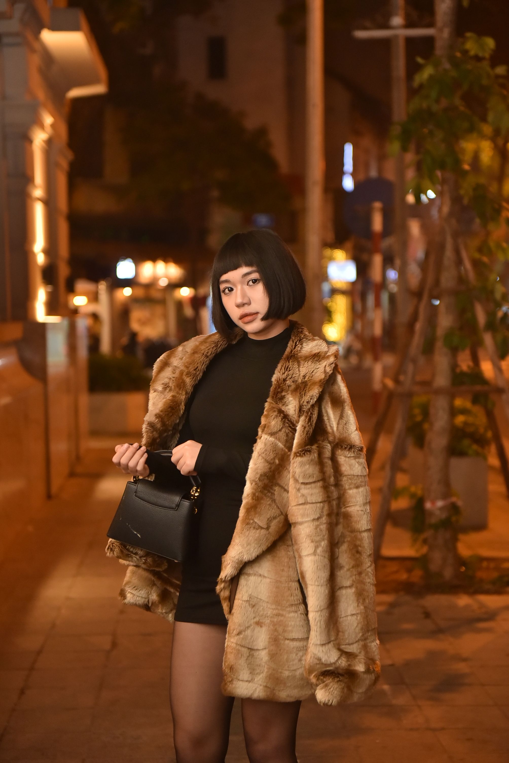 Woman in a fur coat with a little black dress at night