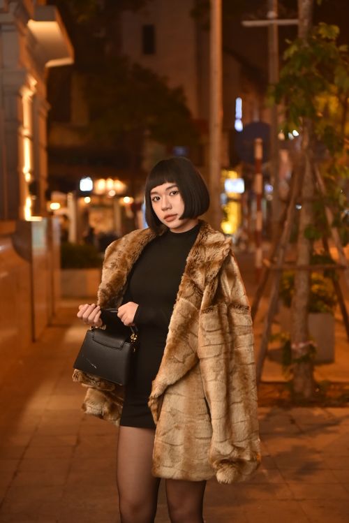 Woman in a fur coat with a little black dress at night