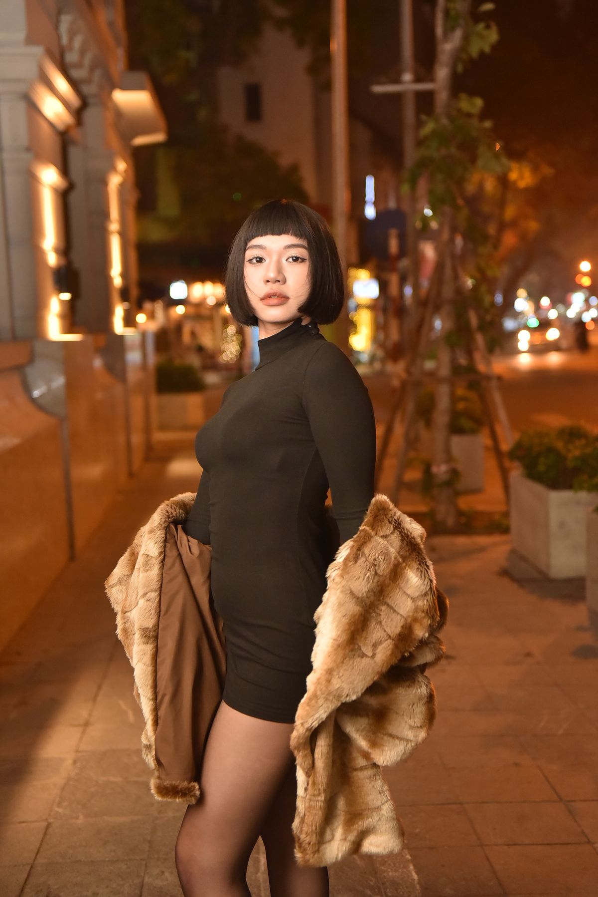 Statement Scarf Outfits for Women — 7 Ways to Style a Scarf as the Star Woman in a black dress and fur coat on a city street at night