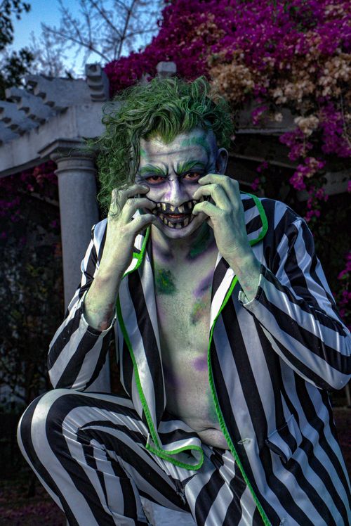 Free A person in green makeup and striped suit poses menacingly outdoors. Stock Photo