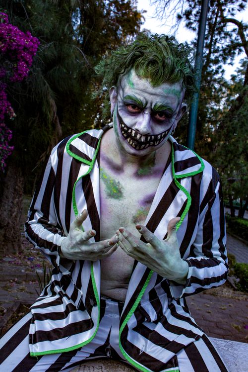 Free Man in black and white striped suit with horror makeup in a park setting posing dramatically. Stock Photo