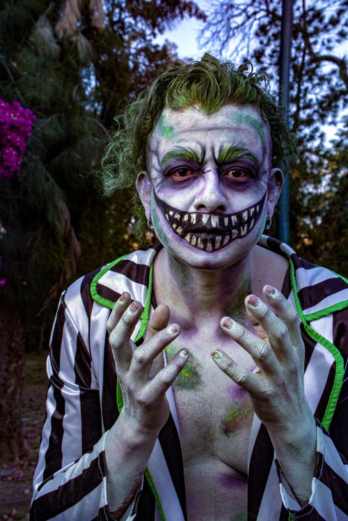 Free Person dressed in joker-inspired costume with vibrant face paint at outdoor setting. Stock Photo