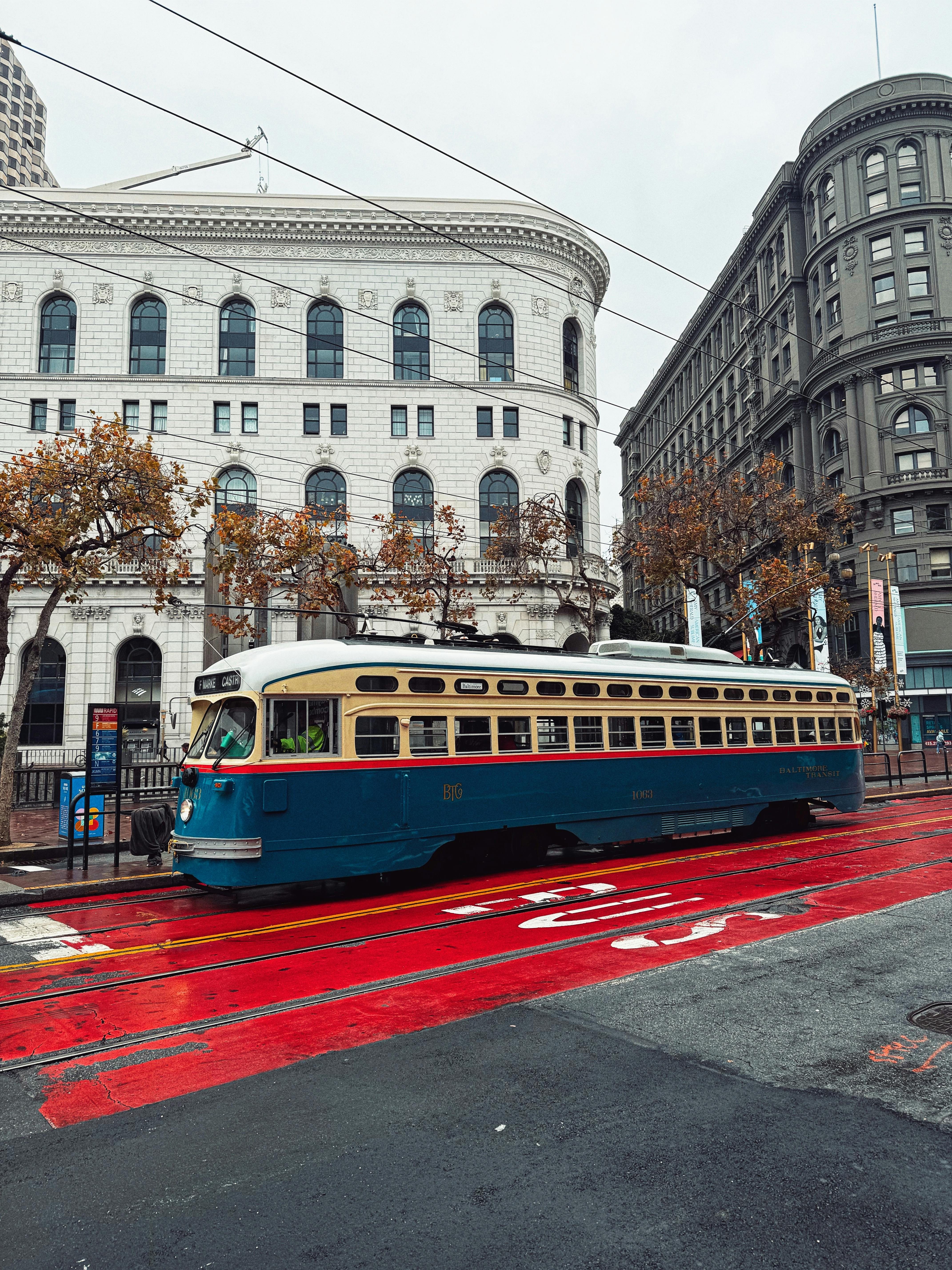 A vintage streetcar travels down a vibrant red track in a historic city setting.