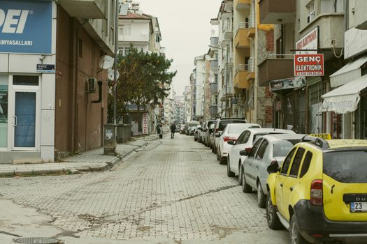 A silent street lined with parked cars and old buildings in an urban setting.