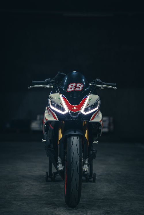 Free A sleek racing motorcycle with bright headlights shot from the front angle in a dimly lit garage. Stock Photo