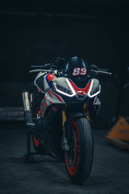 Free Front view of a sleek high-performance motorcycle with racing graphics parked in a dimly lit garage. Stock Photo