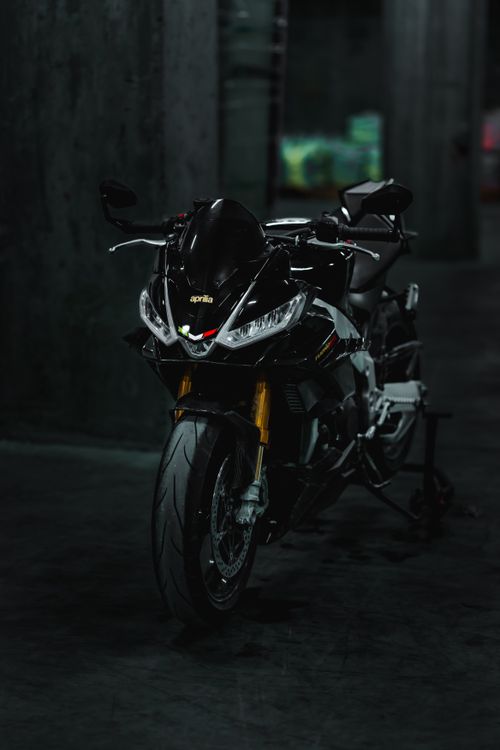 Free A black Aprilia motorcycle showcased in a dark indoor space exuding a powerful presence. Stock Photo