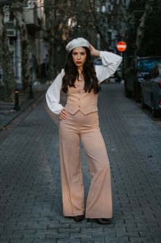 Fashionable woman in a stylish outfit poses on a cobblestone street in Istanbul.