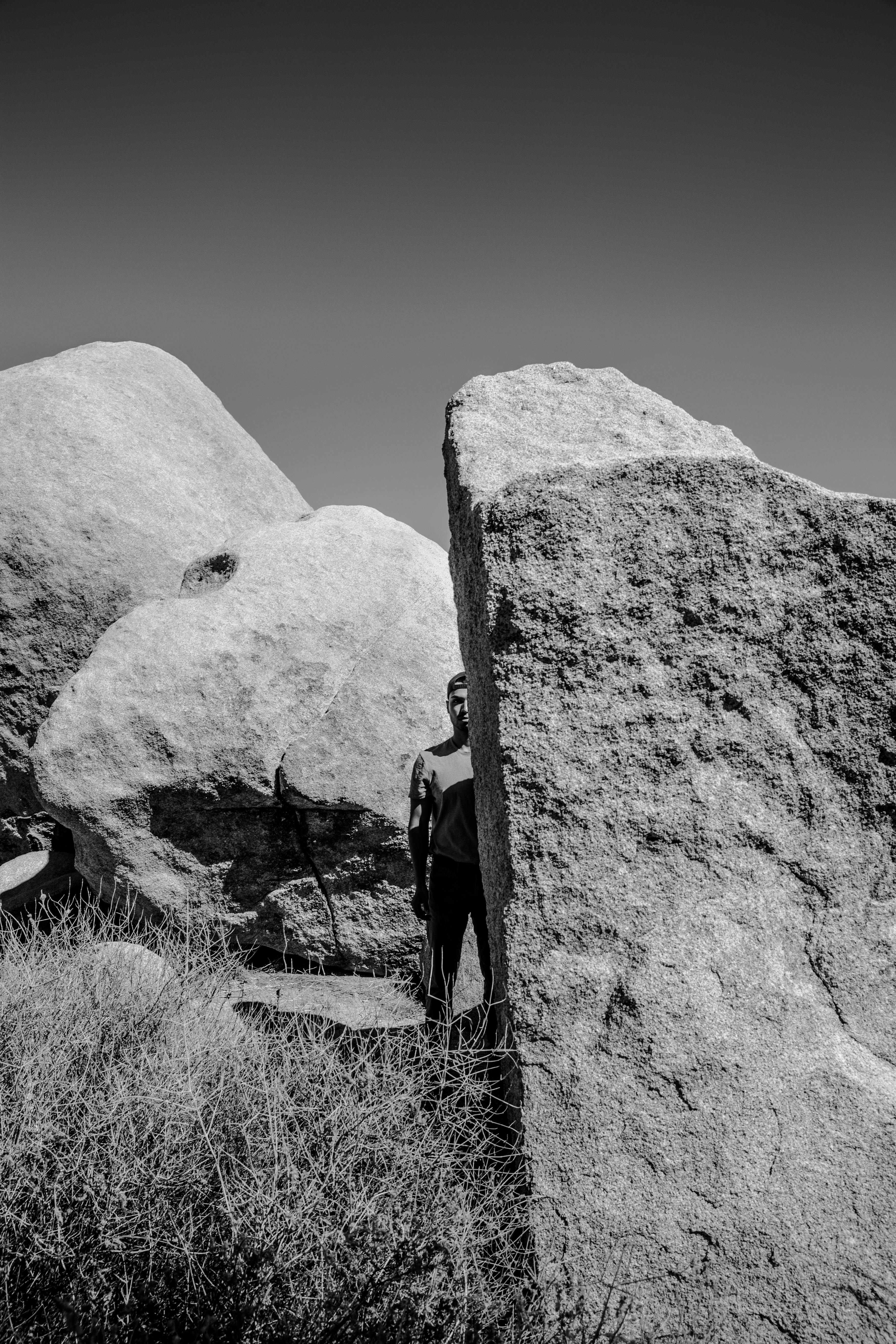 白天，一个人的黑白照片部分被大漠的岩石遮挡着