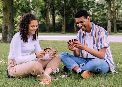 Free Man and Woman Sitting on Grass Playing Cards Stock Photo