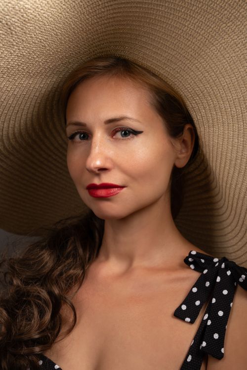 Free Portrait of a stylish woman wearing a wide-brimmed hat and red lipstick, showcasing elegance. Stock Photo