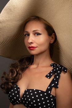 Elegant woman wearing a polka dot outfit and a large sun hat, exuding sophistication.