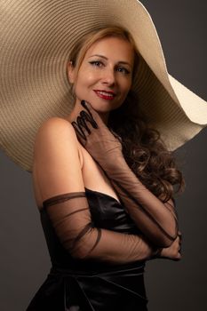 Stylish woman in black dress and hat exuding vintage glamour.