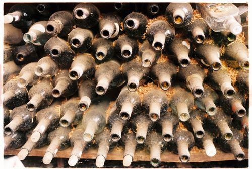 Free A collection of dusty, empty wine bottles stacked horizontally in an old cellar. Stock Photo