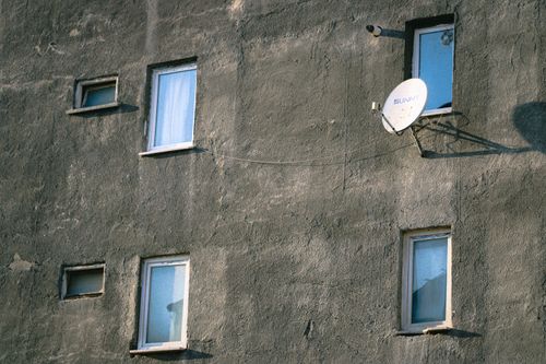 Free Concrete wall with windows and satellite dish, showcasing urban architecture. Stock Photo
