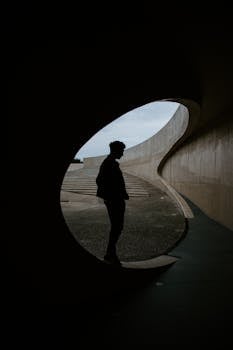 Silhouette of a man standing in a uniquely curved architectural frame, creating a modern urban scene.