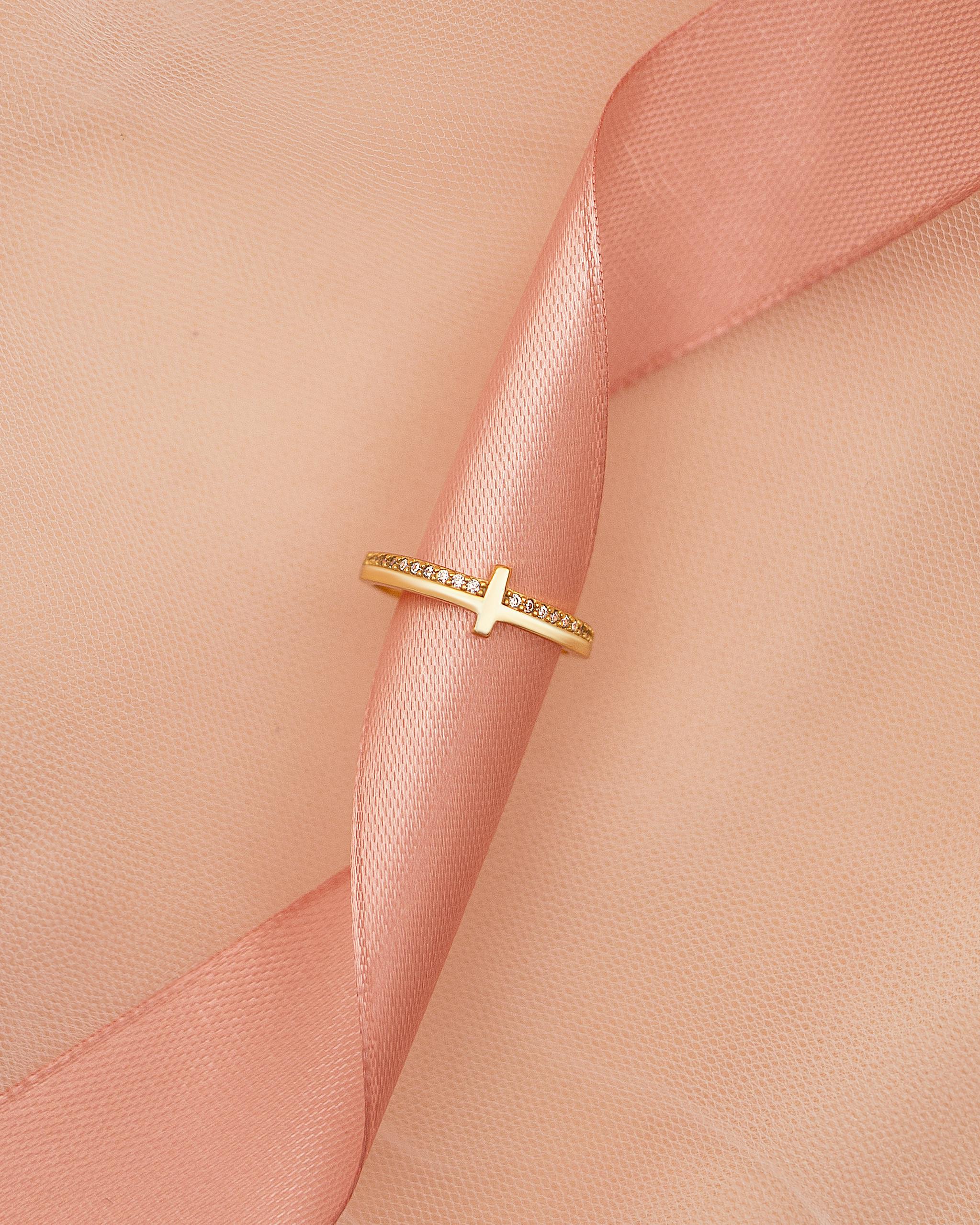 elegant gold ring on soft pink ribbon surface