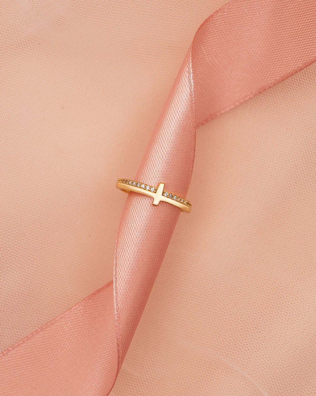Fine gold ring on a softly folded pink ribbon