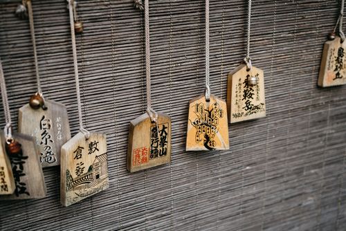 Free Close-up of traditional Japanese ema wooden plaques hanging on a bamboo mat in a shrine setting. Stock Photo