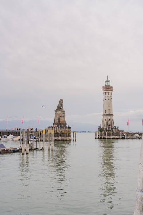 Free Scenic view of Lindau Harbor with iconic Bavarian Lion statue and lighthouse on a cloudy day. Stock Photo