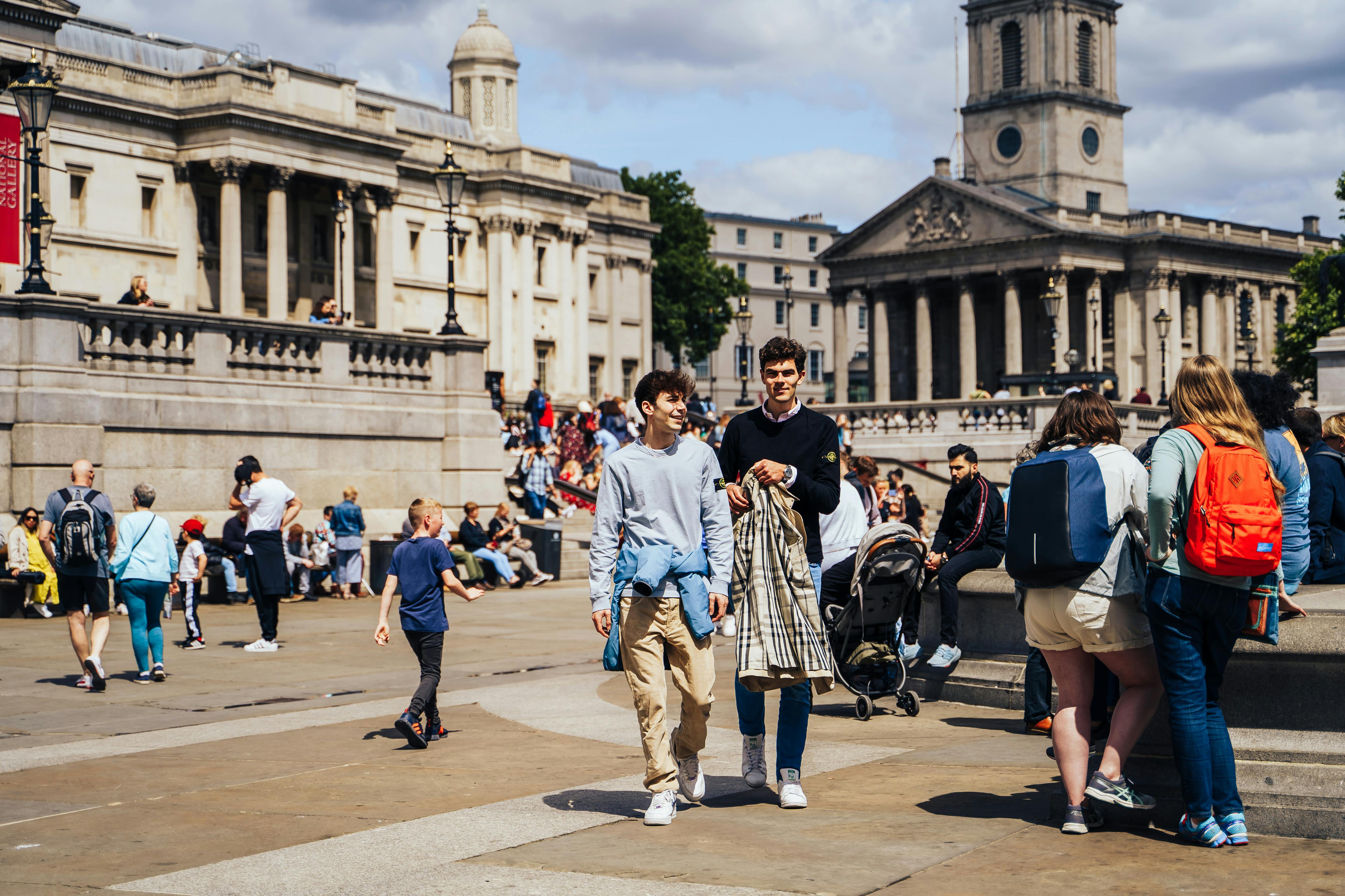 People enjoying a sunny day at Trafalgar Square in London, England.