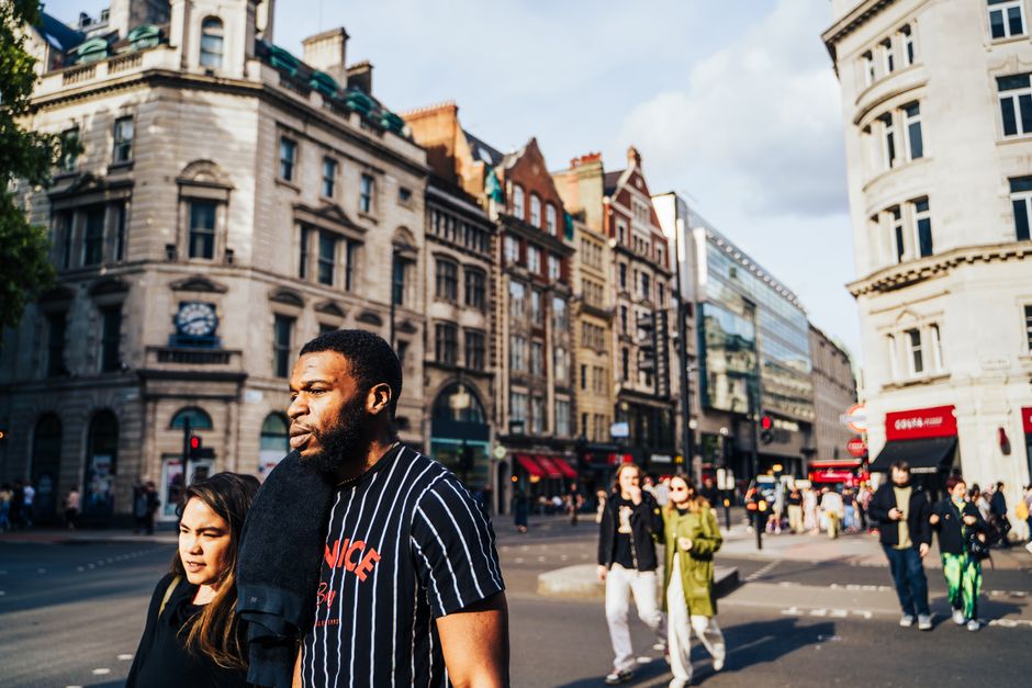 Busy street scene in central London with diverse pedestrians and historic architecture.