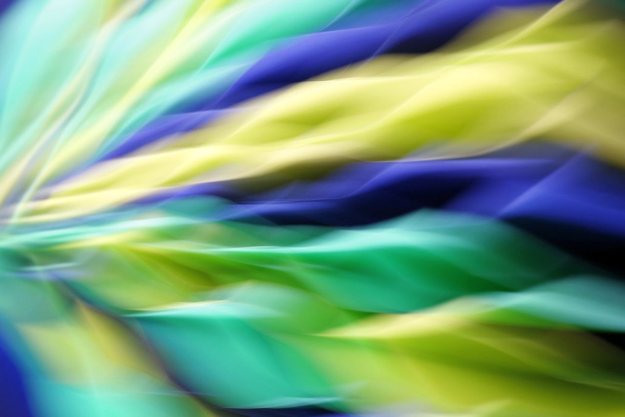 vivid abstract motion blur of colorful fabric waves in blue green and