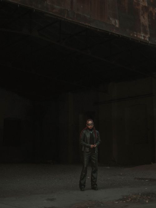 Free A lone figure stands under a dimly lit industrial structure, creating a mysterious atmosphere. Stock Photo