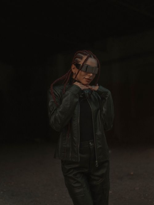Free Stylish portrait of a woman in dark attire and futuristic sunglasses. Stock Photo