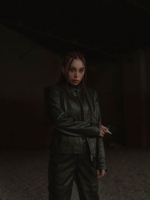 Free Dramatic portrait of a woman in a dark setting, wearing a leather jacket. Stock Photo