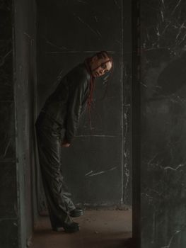 Woman in dark room wearing black outfit, creates a moody artistic vibe.