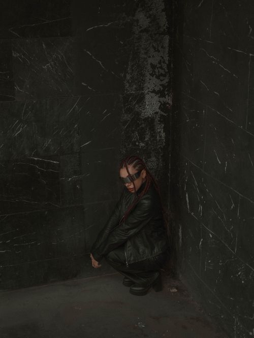Free A person crouching in a dark, textured urban corner with a moody atmosphere. Stock Photo