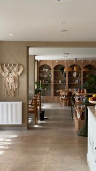 A cozy, sunlit interior featuring a stylish bookshelf, plants, and a minimalist decor.