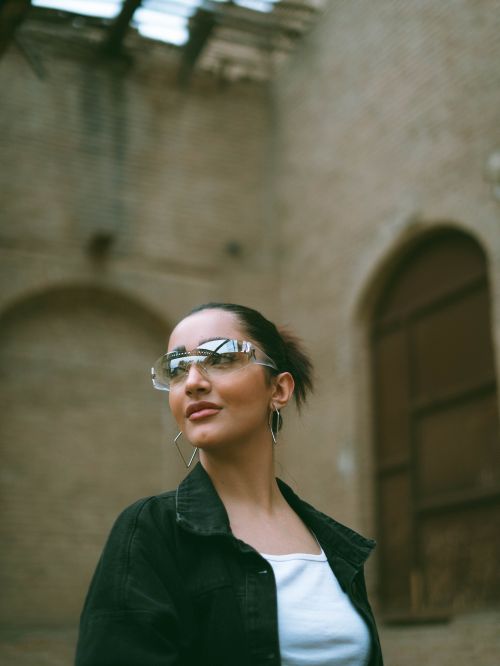 Free Stylish woman wearing reflective sunglasses standing in a rustic urban environment. Stock Photo
